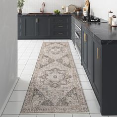 a large rug in the middle of a kitchen with dark cabinets and counter tops on both sides