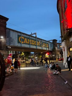 people sitting on the ground in front of a building with a sign that says camden place