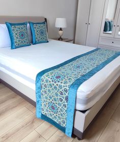 a bed with blue and white pillows on it's headboard in a bedroom