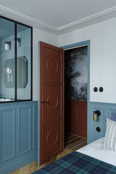 a bedroom with blue painted walls and wood flooring, along with a large mirror on the wall