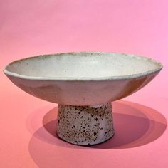 a white bowl sitting on top of a pink surface