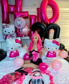 a woman sitting on top of a bed in front of hello kitty balloons and decorations