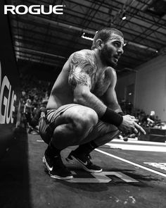 a man squatting on the ground in front of a crowd