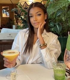 a woman sitting at a table with a drink