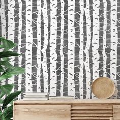 a white and black wallpaper with trees on it, next to a wooden dresser