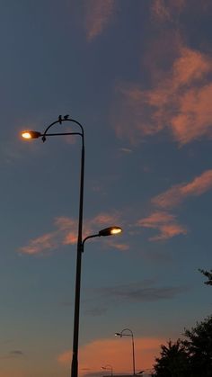 the street lights are lit up at night in front of an orange and blue sky