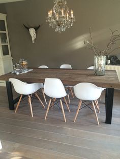 a dining room table with white chairs and a chandelier