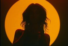 the silhouette of a woman in front of a yellow circle