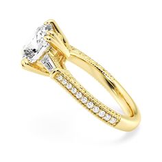 a yellow gold engagement ring set with a princess cut center stone and side stones on the band