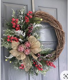 a wreath with red berries and greenery hangs on the front door