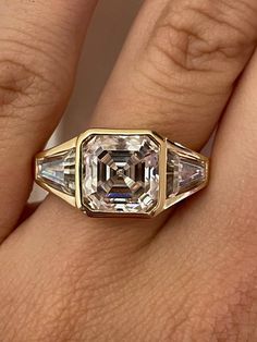 a woman's hand with a ring that has an emerald and white diamond in it