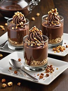 three desserts with chocolate frosting and nuts on the top are sitting on plates