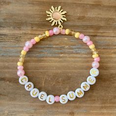 a beaded bracelet with the word summer written on it and a gold sun charm