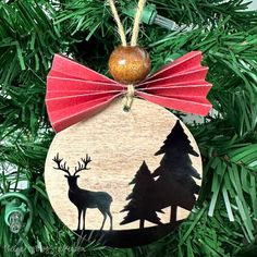 a wooden ornament hanging on a christmas tree with red bow and deer silhouettes