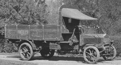 an old truck is parked on the side of the road in front of some trees