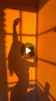 the shadow of a woman standing in front of a wall with her hand up to the side