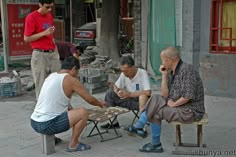 three men sitting at a picnic table talking to each other