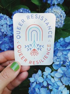 someone is holding up a sticker that says outer resilince with blue flowers in the background