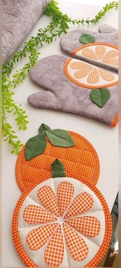 three oranges are on the table and one is made out of fabric with green leaves