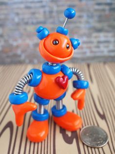 an orange and blue robot toy next to a penny