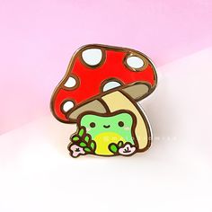 a mushroom pin with an image of a green creature in it's center on a pink background