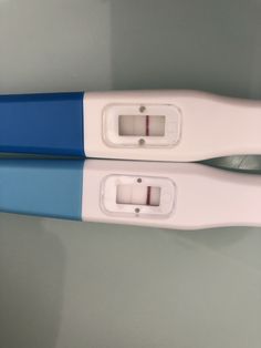 two blue and white toothbrushes sitting next to each other on a gray surface