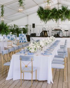 a table set up with blue and white linens for a wedding reception in a marquee