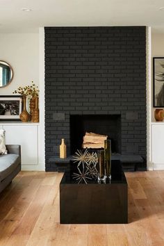 a living room filled with furniture and a fire place in front of a black brick wall