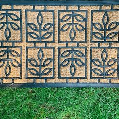 a close up of a door mat on the ground with grass in front of it