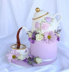 there is a cake with flowers on it and a tea pot