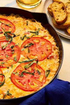 an omelet with tomatoes and basil in a pan next to some slices of bread