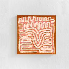 an orange and white painting on a wall next to a brown square with lines in it