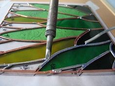 a piece of stained glass being worked on with a metal tool and some other tools