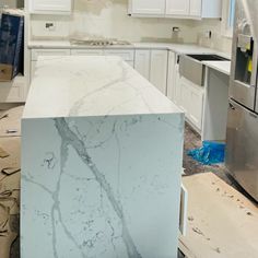 a kitchen with white cabinets and marble counter tops in the process of remodeling