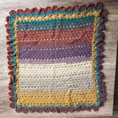 a multicolored crocheted blanket on top of a wooden table