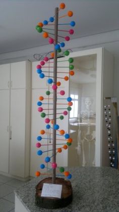 a multicolored tree is on display in the middle of a room with white cabinets