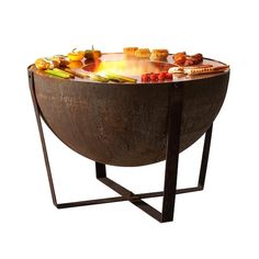 an outdoor fire pit with lots of food on the top and around it's sides