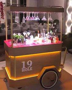 an old fashioned bar cart with wine glasses on the top and liquor bottles behind it