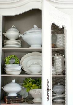 a white china cabinet filled with lots of dishes