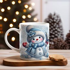 a coffee mug with a snowman on it next to a cookie and christmas tree