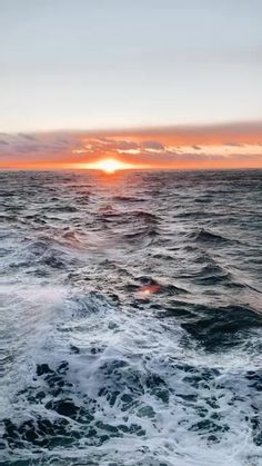 the sun is setting over the ocean as seen from a boat in the water with foamy waves