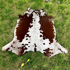 a brown and white cow skin laying on top of green grass