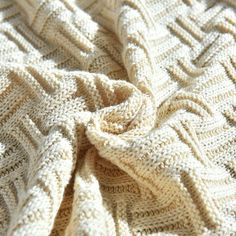 a white knitted blanket laying on top of a bed