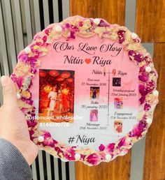 a person holding up a pink and white plaque with pictures on it that says our love story, nin rija