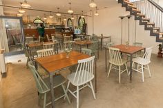 an empty restaurant with tables and chairs next to stairs leading up to the second floor