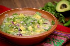 a wooden bowl filled with guacamole next to an avocado