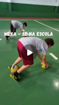 two young boys playing with soccer balls on a green floor in an indoor gym area