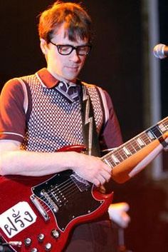 a man with glasses playing an electric guitar