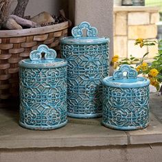 three blue canisters sitting next to each other on a stone slab with flowers in the background