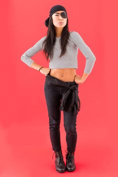 a woman in black pants and striped shirt posing for the camera with her hands on her hips